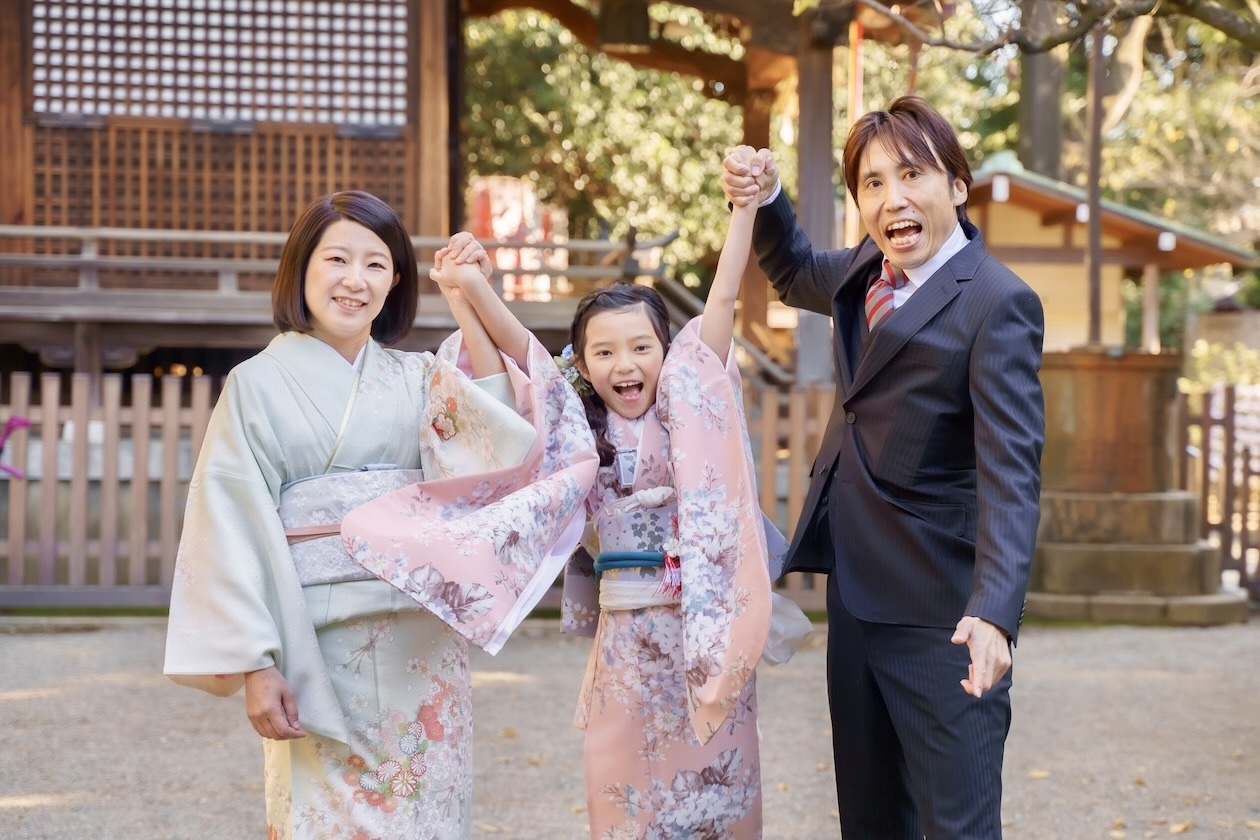 代々木八幡宮の７歳の七五三の写真。パパとママと手を繋いで笑顔のご家族です。